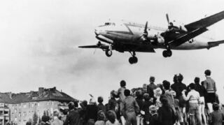 Ein Foto mit geradezu ikonischer Bedeutung: Auf Kriegstrümmern jubeln Berliner Kinder 1948 den amerikanischen Flugzeugen mit ihrer rettenden Ladung zu.