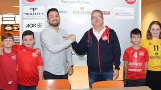 Besiegeln die Fortführung ihrer Partnerschaft während des HG-Powercamps im Kreise einiger HG-Kids: Andreas Funkert (AOK, l.) und HG-Vorstandsmitglied Michael Zipf.