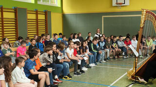 Die Zeyher-Grundschüler sind begeistert vom Harfenspiel in der Turnhalle und von dem tollen Instrument.