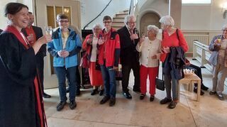Pfarrerin Christiane Banse feiert mit Gottesdienstbesuchern, die sich in Rot gekleidet haben, den Geburtstag der Kirche – ein Glas Sekt gibt’s dazu natürlich auch.