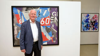 Manfred Fuchs vor einer Collage aus alten Plakatfragmenten, die er selbst an verwais-ten Plakatflächen absammelt.