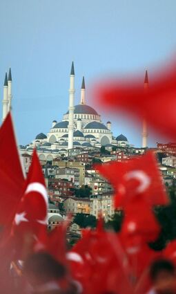 Menschen schwenken türkische Fahnen. Im Hintergrund ist die Camlica-Moschee zu sehen.