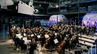 Klassik an ungewöhnlichen Orten spielen: Die Deutsche Staatsphilharmonie Rheinland-Pfalz im Technik Museum unter dem Space Shuttle „Buran“.