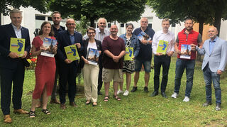 Matthias Steffan (v. l.), Maike Berkemaier, Ramon Eck, Dr. René Pöltl, Silke Feurer, Dr. Michael Rittmann, Werner Zieger, Sarina Klein, Carsten Petzold, Dr. Christian Lorentz, Robin Pitsch und Haydar Sahin präsentieren mitten im Grün des Rathaushofes die Broschüre der Klimakampagne 2024.