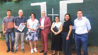Hinter diesem Zaun soll die neue Tennishalle entstehen. Darauf freuen sich Klaus Heinrichs, Architekt Jürgen Roth, Vorsitzende Janine Breyer, Bürgermeister Matthias Steffan, Sachgebietsleiterin Silke Feurer vom Amt für Bauordnung und Wirtschafts-förderung, ihre Kollegin Regine Raband (Liegenschaften) und TC-Schatzmeister Oliver Faulhaber.