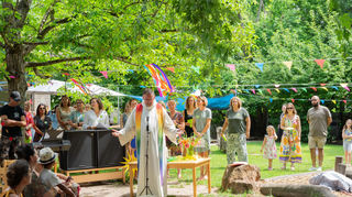 Pfarrer Uwe Lüttinger läutet das Fest im katholischen Kindergarten St. Martin mit einem Gottesdienst ein, den die kleinen und großen Besucher bei sommerlichem Wetter im bunt geschmückten Garten feiern.