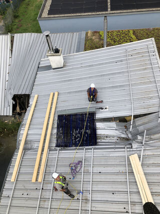 Um einen Wasserschaden zu vermeiden, verschließen die Dachdecker das Loch mit Balken und einer Folie.