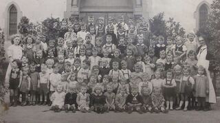 Das Bild entstand um 1948 und zeigt alle Kinder des Josefshaus-Kindergartens vor der Kirche St. Kilian zusammen mit der Kindergärtnerin Maria Klee-Rauchholz (l.) und „Kinnerschulschweschder“ Nevulana.