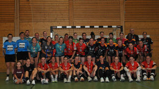 Die Spielerinnen der Flames HSG Bensheim/Auerbach (dunkle Trikots) und der HSG St.Leon/Reilingen (rote Trikots), gemeinsam mit Trainern und Schiedsrichterinnen auf einem Gruppenfoto.
