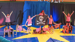 Piraten bauen kleine Menschenpyramiden: Kunterbunt, artistisch und voller Unterhaltung läuft die „Kulturbühne“ der Ketscher Schule mit dem Thema „Zirkus Neurotti“ ab. Die anwesenden Eltern, Freunde und Lehrer sind vollauf begeistert.