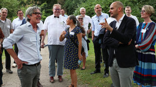 Finanzminister Dr. Danyal Bayaz besucht mit SSG-Geschäftsführerin Patricia Alberth während seiner Sommertour mal wieder den Schwetzinger Schlossgarten. Prof. Dr. Hartmut Troll (l.) erläutert hier das römische Wasserkastell.