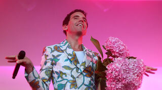 Mika lächelt glückselig von der Bühne. Hier hat er die Blumen seiner Fans im Arm und startet gleich zu einem fulminanten Konzert.