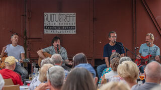 Andreas Bock (v.l.), Seán Treacy, Stefan Buchholz und Claus Bubik sorgen für blendende Stimmung im Biergarten des Alten Bahnhofs.