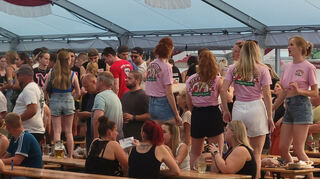Eine der vielen Gruppen in den legendären „Bierkönig“-Shirts. Die Frauen brauchen nicht lange, bis sie auf den Bänken mitfeiern. Bild: Feth