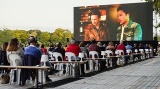 Zuschauer verfolgen beim Festival des deutschen Films auf der Parkinsel auf einer großen LED-Videoleinwand einen Kinofilm.