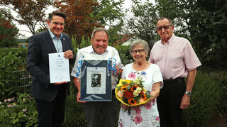 Bürgermeister Stefan Weisbrod (l.) und der frühere Oberbürgermeister von Hockenheim, Gustav Schrank (r.) gratulieren Ehrenbürger Helmut Müller zum 80. Geburtstags und für seine Frau Waltraud Müller gibt es einen bunten Blumenstrauß.