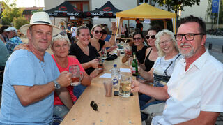 Ralf (v.l.), Ingrid, Saskia, Sarah, Stephanie, Katharina, Jutta und Heiner lassen es sich auf dem Rathausplatz gut gehen, genießen den Abend beim Weinfest des SC 08. Bild: Lenhardt