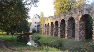 Das Untere Wasserwerk mit einem Aquäduktarm des Römischen Wasserkastells entlang des Bachlaufs.