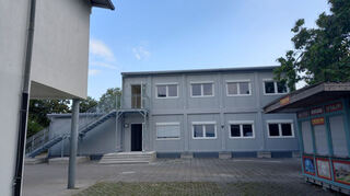 Die neuen Container von außen auf dem vorderen Schulhof. Mit ihnen kann die Raumkapazität der Schule gedeckt werden, auch wenn dies zu Lasten des Pausenhofs geht.