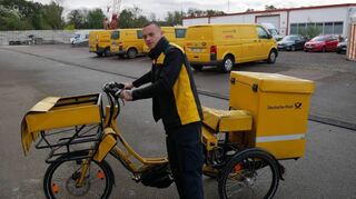 Zusteller Lenny Lorz mit seinem gelben „E-Trike“, das insgesamt bis zu 120 Kilogramm Briefpost tragen kann.
