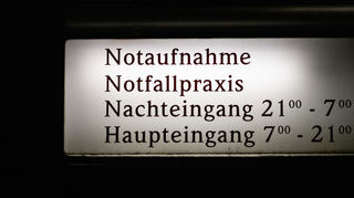 EIn Schild weist auf die Notaufnahme, die Notfallpraxis und Eingangszeiten eines Krankenhauses hin.