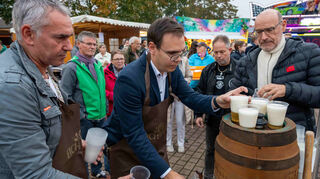 Bürgermeister Kevin Weirether (Bildmitte) hat die angenehme Pflicht, nach dem gelungenen Fassbieranstich das Freibier auf der Kerwe in Neulußheim auszuschenken.