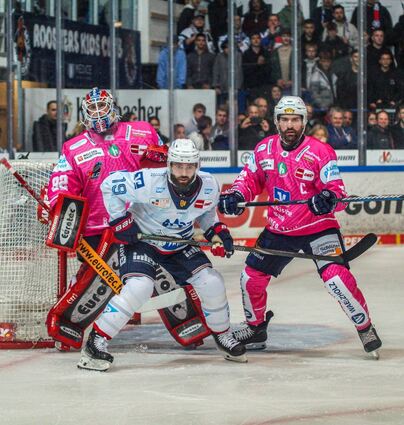 Luke Esposito (weißes Trikot) versucht, Iserlohns Torhüter Andreas Jenike die Sicht zu nehmen. Roosters-Kapitän Hubert Labrie rückt dem Adler-Stürmer auf die Pelle.