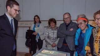 Museumsleiter Lars Maurer (l.) und einige Gäste betrachten das „Lebende Buch“, das in Zukunft im Museum am Alten Messplatz zu sehen sein wird.