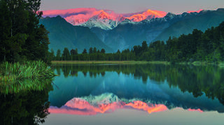 Traumziel: der Lake Matheson nahe der Westküste der Südinsel Neuseelands. Er ist berühmt dafür, dass von Nordwesten gesehen sich Aoraki/Mount Cook und Mount Tasman auf der Wasseroberfläche spiegeln.