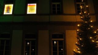 Die ersten beiden Kalender-Motive werden am Plankstadter Rathaus feierlich illuminiert. Der Adventskalender verwandelt die Fenster bereits seit zwei Jahrzehnten in verschiedene Bilder der Christusgeschichte.