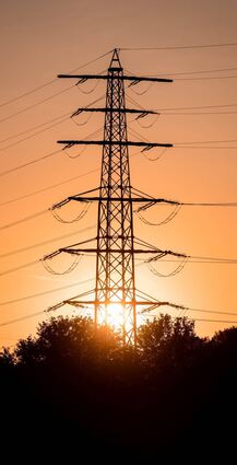 Die Sonne geht hinter einem Strommast unter: In den Abendstunden ist der Strom üblicherweise teurer.