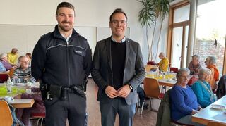 Erster Polizeihauptmeister Tobias Hoffmann wird von Bürgermeister Kevin Weirether bei der Veranstaltung des Forums „Aktiv im Alter“ im evangelischen Gemeindehaus begrüßt.
