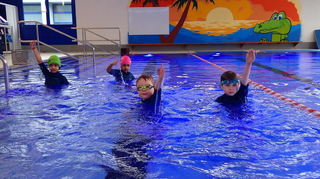 Kabir, Vihana, Frederik, Moritz, Hanna und Emma üben im Lehrschwimmbecken Armkreise für das Kraul- und Rückenschwimmen.