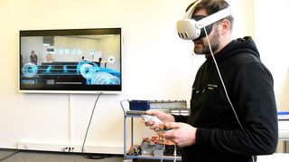 Trainer Roman Bieniek demonstriert, wie VR-Brillen bei den Schulungen für Beschäftigte unterstützen können.