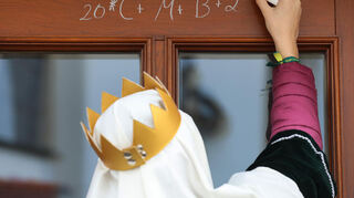 Sternsinger sind am Dreikönigstag unterwegs und schreiben mit Kreide «20 C+M+B 24», die aktuelle Jahreszahl und die Initialen der Könige als Segenspruch an eine Tür (Symbolbild).