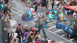 Narren ziehen beim Faschingsumzug durch die Stadt und feiern ausgelassen.