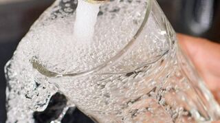 Am Wasserhahn in einer Küche wird ein Trinkglas mit Leitungswasser befüllt (Symbolbild).