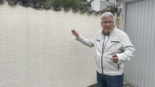 Volker Engelfried zeigt auf die Mauer seines Grundstücks, in der immer wieder neue Risse auftauchen.