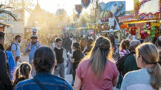 Die Frühjahrsmesse lockt bereits am Eröffnungstag zahlreiche gut gelaunte Besucher auf den Festplatz Speyer. Die untergehende Abendsonne bringt schöne Lichtstimmungen in den Gassen zwischen den Buden hervor.