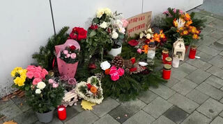 Blumen und Kerzen standen vor einem Hauseingang in Erinnerung an die Opfer. Nach der Tötung einer Mutter und ihrer Töchter in Berlin-Marzahn steht der Partner und Vater in Berlin vor Gericht.