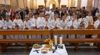 Für die Gabenbereitung brachten Kommunionkinder an den Altar, was man für einen schön gedeckten Tisch braucht.