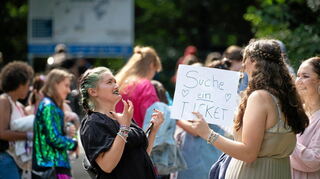 Taylor-Swift-Fans auf der Suche nach einem Ticket vor einem Konzert im Volksparkstadion in Hamburg – auf dem sogenannten Ticket-Zweitmarkt. Auch online gibt es einen solchen.