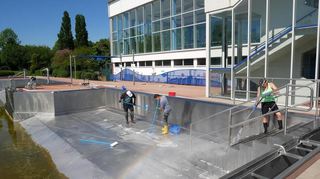 Links die dunklen Ablagerungen des Winters, rechts der glänzende Edelstahl: Mit Putzmittel und Hochdruckreiniger sorgt das Bäderteam im Schwimmerbecken für die alljährliche Grundreinigung.