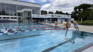 Mit einem beherzten Sprung taucht Bastian Distler ins Wasser und bringt die neue Schwimmleine in Position - die Schwimmbadfreunde sind begeistert.