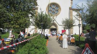 Der Kirchgarten von St. Kilian im Baustellen-Outfit, dazwischen die Gottesdienstbesucher, teils auf Picknickdecken.