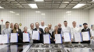 Nach der Übergabe der Urkunden kommen die frischgebackenen Meister mit den Prüfern in der Küche der Heidelberger Hotelfachschule zum Gruppenbild zusammen.
