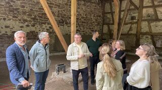 Laurin Schulze (M.) erklärt den Vertretern der Stadt, der Stadtwerke und der Presse den Baufortschritt in der alten Scheune.