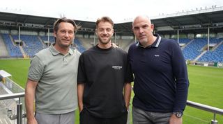Lukas Klünter (Mitte) vor dem Spielfeld.