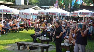 Unter den Sonnenschirmen sind die Sitzplätze von Country-Fans belegt.