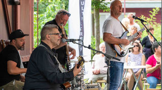 Olli Roth (vorn an der Gitarre) und seine Band heizen im Garten des Alten Bahnhofs bei regnerischem Wetter den zahlreichen Besuchern richtig ein.